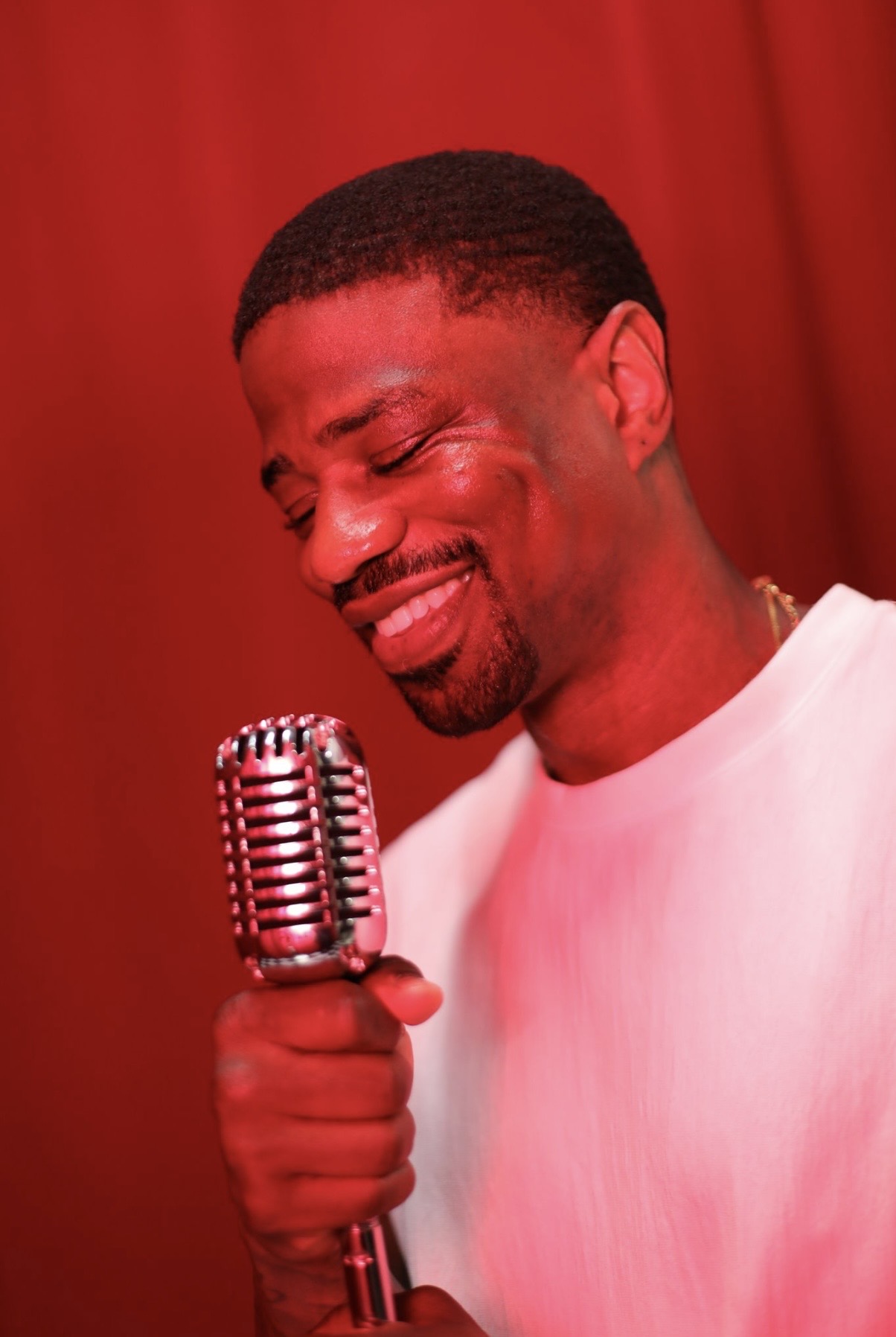 Arion Johnson holding a vintage microphone against a red background